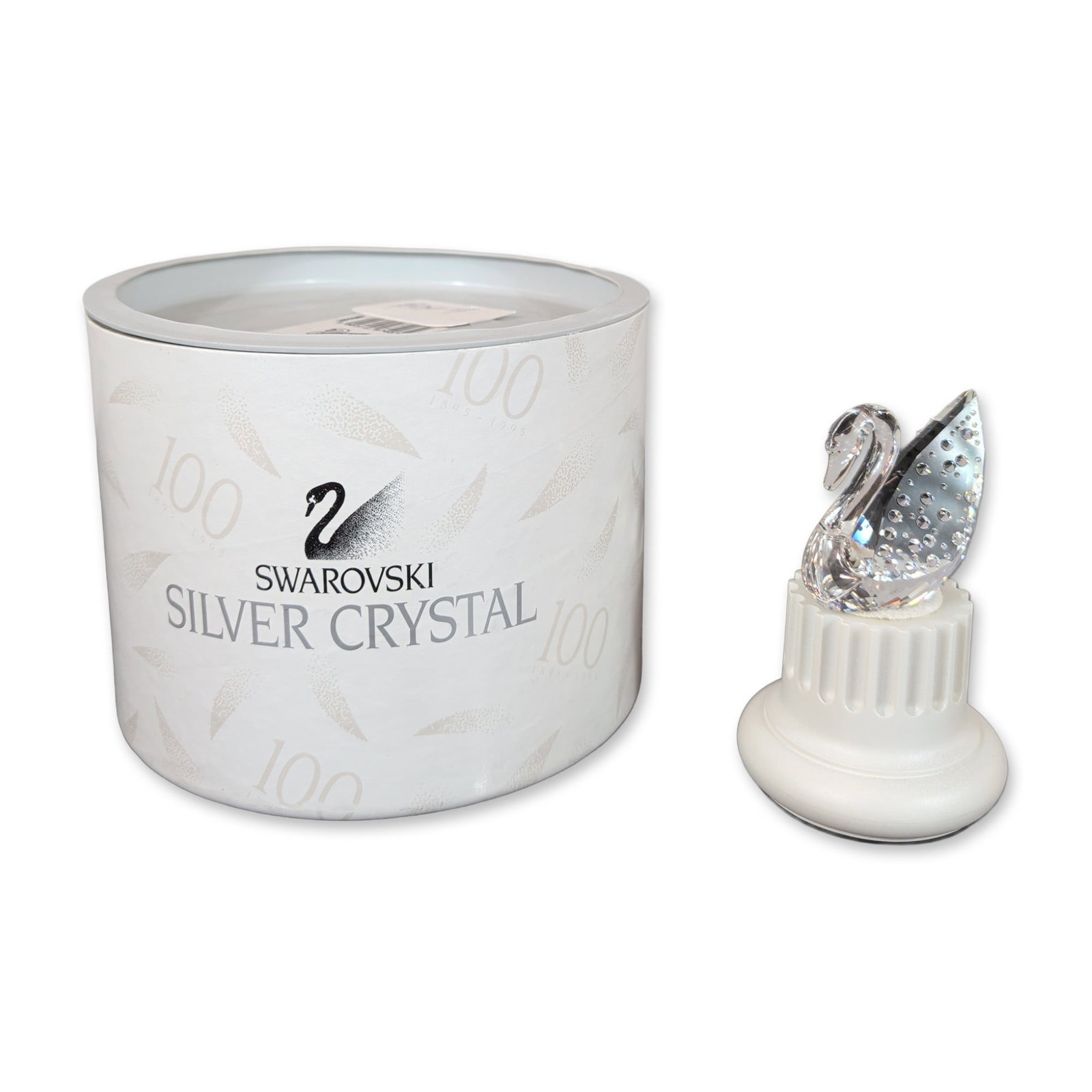 Swarovski Centenary Swan Crystal Figurine with Base: Centenary Swan figurine in faceted lead crystal with a smooth arched neck, resting on a white fluted columnar display base. Produced in 1995 to commemorate the 100th anniversary of the company (1895��