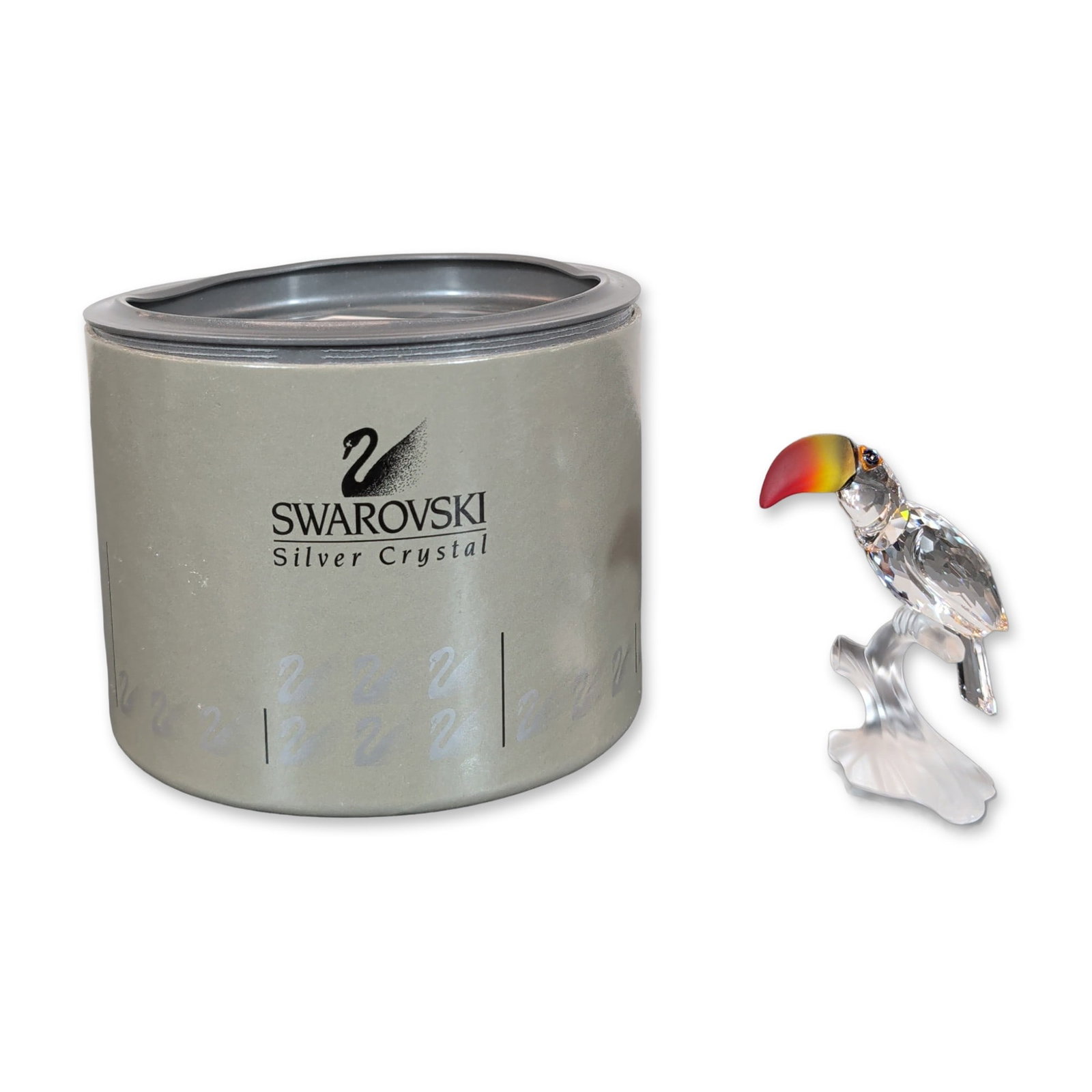Swarovski Silver Crystal Toucan Figurine: Swarovski Silver Crystal toucan figurine faceted clear crystal with a multi-colored red and yellow gradient beak and black bead eyes, perched on a frosted glass branch. Features an etched swan logo an