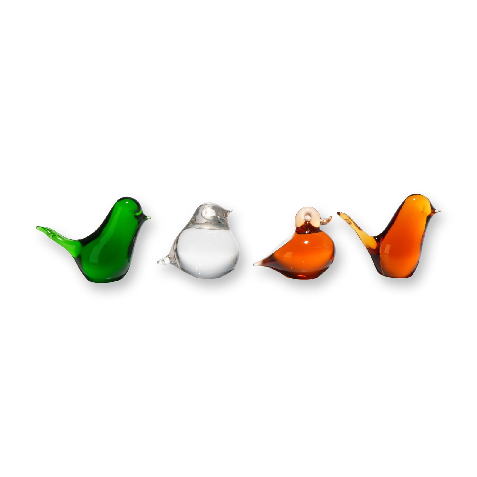 4pc Wedgwood Glass Bird Paperweights: A set of four art glass bird figurines produced by Wedgwood. These hand-formed paperweights comprise four distinct stylized forms: one songbird in translucent emerald green glass with an upturned