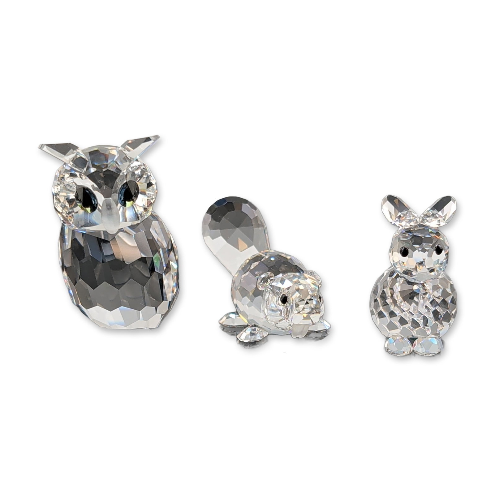 Three Swarovski Silver Crystal Animal Figurines: Swarovski faceted lead crystal animal figurines from the Silver Crystal line. Assortment includes an owl with frosted beak and dark eyes, a seated rabbit, and a beaver with textured paddle tail. Each 