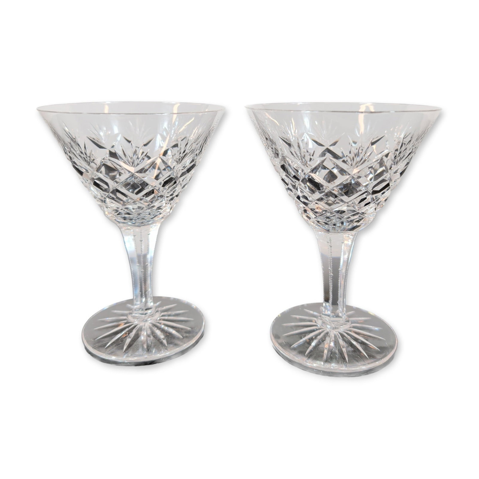 Pair of Cut Crystal Champagne Glasses: Pair of cocktail glasses, crafted from cut lead crystal. The bowls feature deep-cut criss-cross diamond motifs around the base, surmounted by vertical fan cuts toward the rims. Stems are