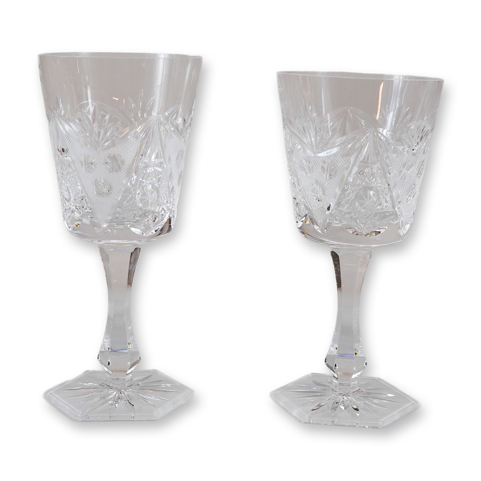 Pair of Cut Crystal Decorated Wine Glasses with Faceted Stems and Hexagonal Feet: A pair of cut crystal wine glasses or goblets. The pieces feature deep hand-cut decoration on the bowls characterized by triangular panels of fine strawberry diamond cutting, divided by deep miter