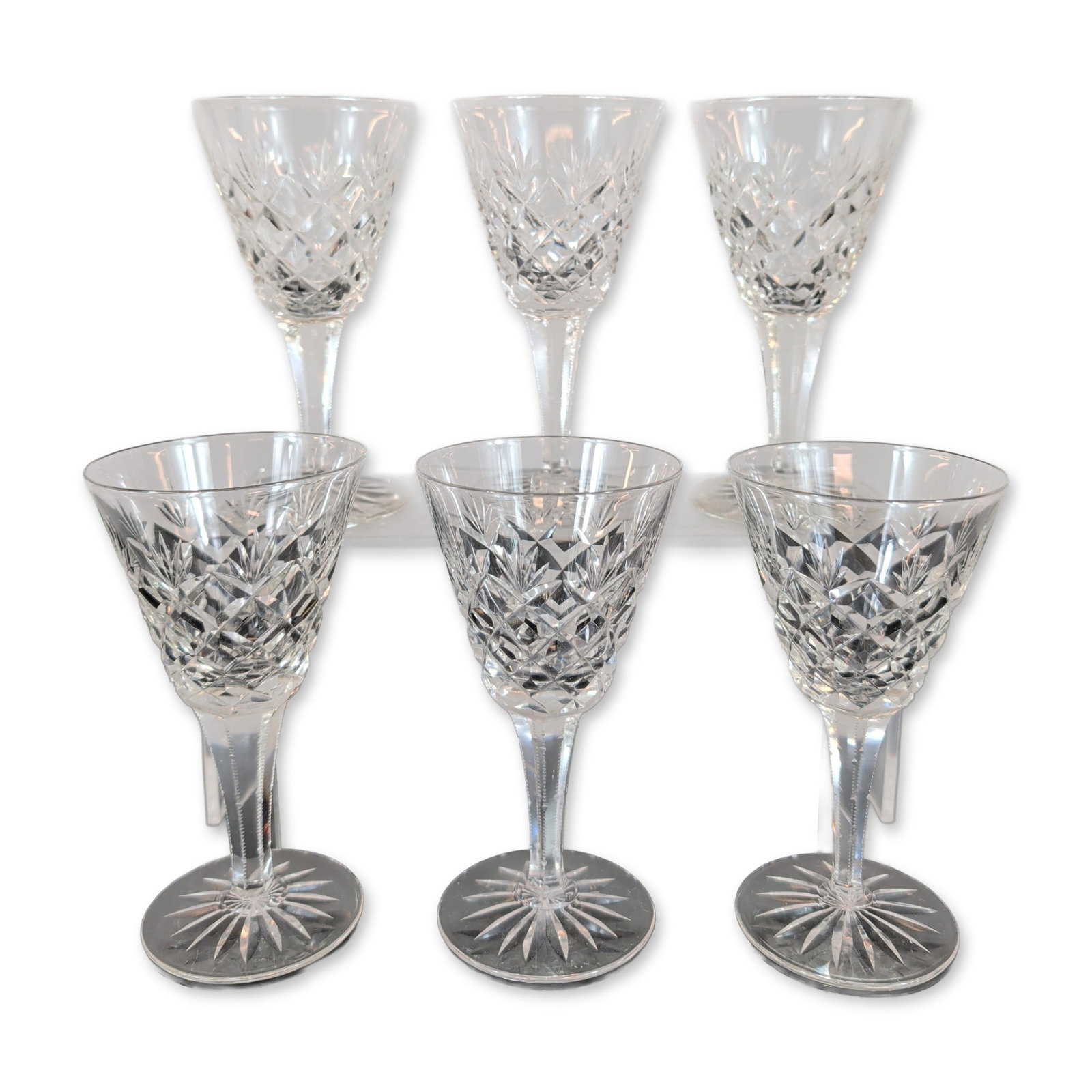 Set of Six Cut Crystal Sherry Glasses: Set of six cut lead crystal Sherry glasses. Each piece features a flared bowl decorated with a band of diamond cross-hatch cuts beneath elongated vertical wedge cuts. The faceted stem includes