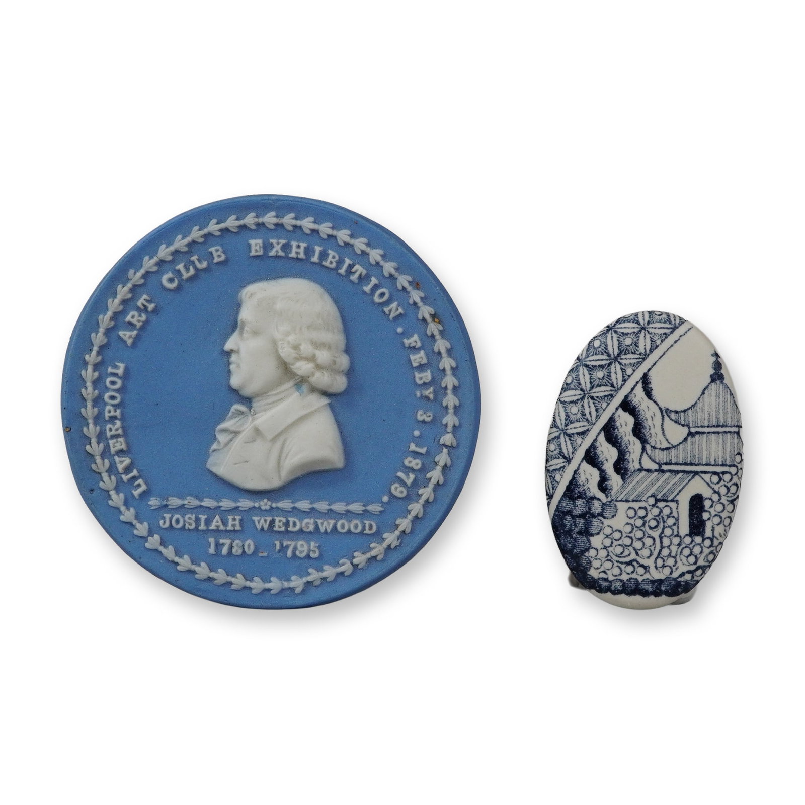 Two Wedgwood Ceramic Medallions: The first is a circular blue jasperware commemorative medallion with white sprigged bas-relief decoration. It depicts a profile portrait of Josiah Wedgwood in the center. The surrounding text in