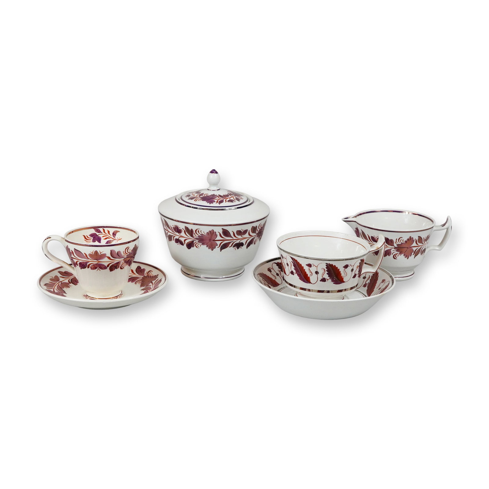 6pc Wedgwood Luster Decorated Creamware Partial Tea Service: This partial tea service is manufactured by Wedgwood in Etruria, England, and is decorated in a hand-painted stylized foliate and floral scroll pattern using pink and copper-toned metallic luster. The