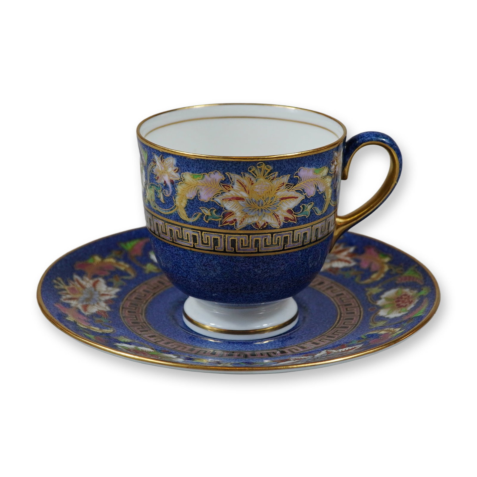 2pc Wedgwood Blue Siam Bone China Footed Teacup and Saucer: A Wedgwood fine bone china footed teacup and saucer in the Blue Siam pattern. The set features a deep cobalt blue ground decorated with hand-painted polychrome enamel floral motifs, including stylized