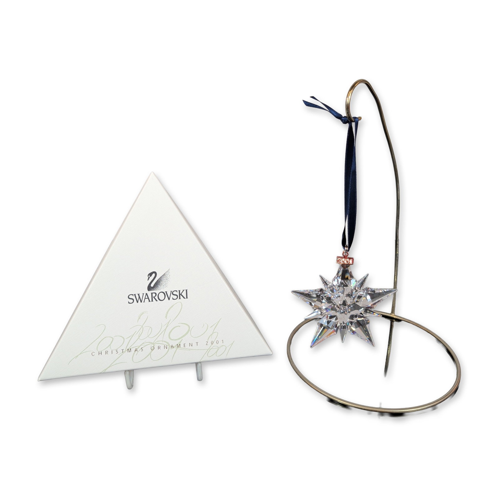 Swarovski 2001 Annual Edition Crystal Star Ornament: Annual Edition Christmas ornament in faceted lead crystal, designed as a multi-pointed star with alternating long and short tapered points radiating from a central hub. Piece is suspended from a navy-