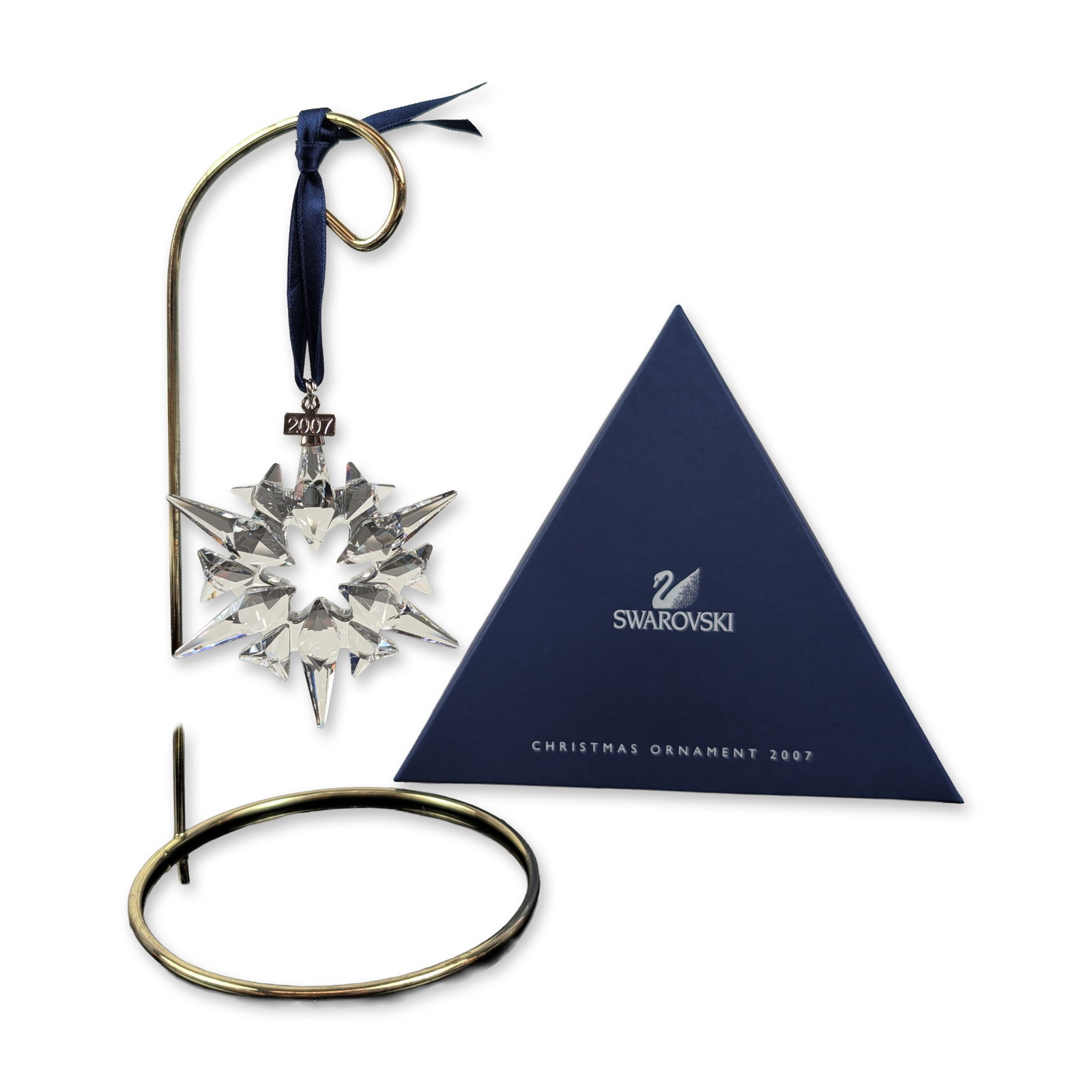 Swarovski 2007 Annual Crystal Star Ornament: Swarovski Annual Edition Christmas star ornament in faceted clear lead crystal, featuring a multi-pointed star design. Suspended from a navy blue satin ribbon with silver-tone metal components, includ
