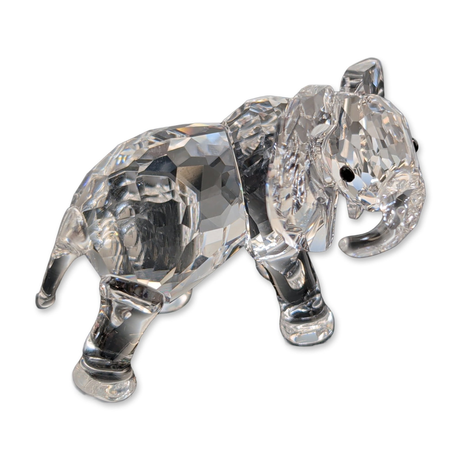 Swarovski Silver Crystal Figurine, Little Elephant: Swarovski Silver Crystal Elephant figurine in faceted clear crystal, depicting a baby elephant in a dynamic pose with a raised front leg and turned trunk. Features large ears and inset black crystal e