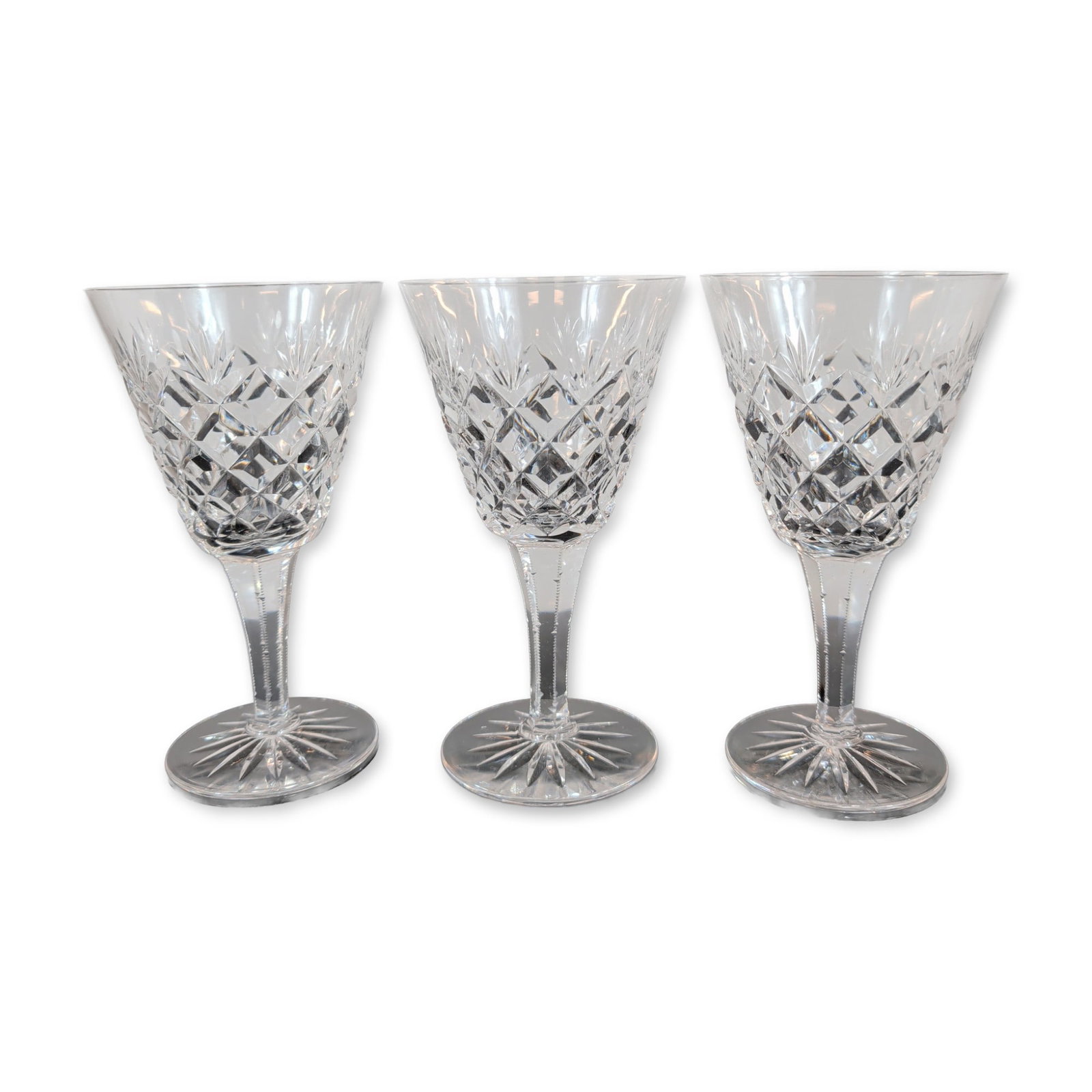 Trio of Crystal Goblets: Three goblets featuring hand-cut criss-cross diamond patterns on the lower bowl transitioning to vertical wedge cuts at the rim. The faceted stems taper to a circular foot with a sixteen-point radial 