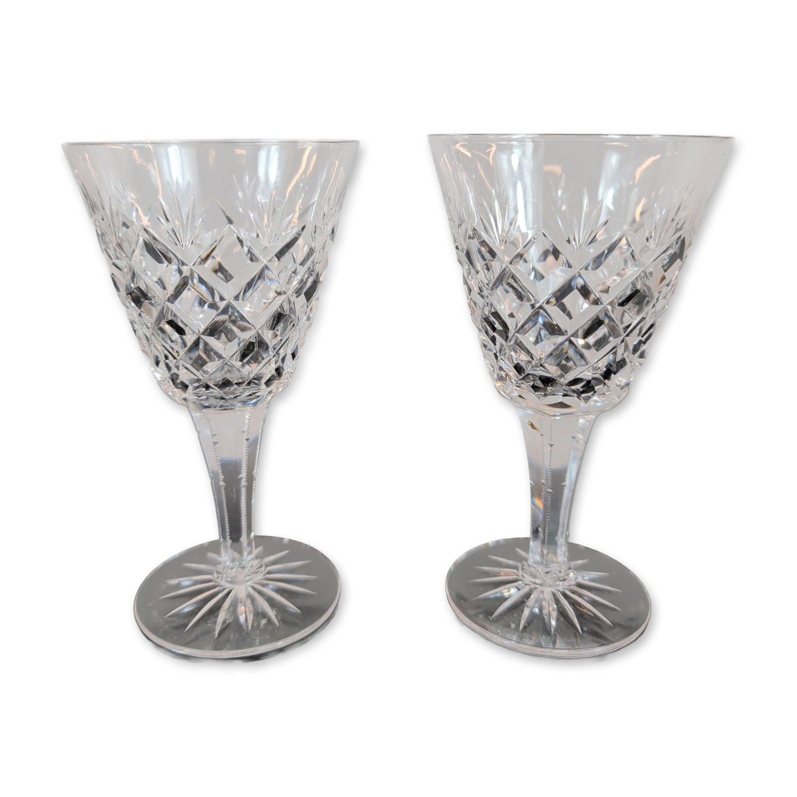 Pair of Crystal Wine Glasses: Pair of wine glasses, crafted in lead crystal. The bowls feature a lower band of deep-cut diamond patterns surmounted by vertical wedge cuts. The six-sided faceted stems lead to circular feet finished
