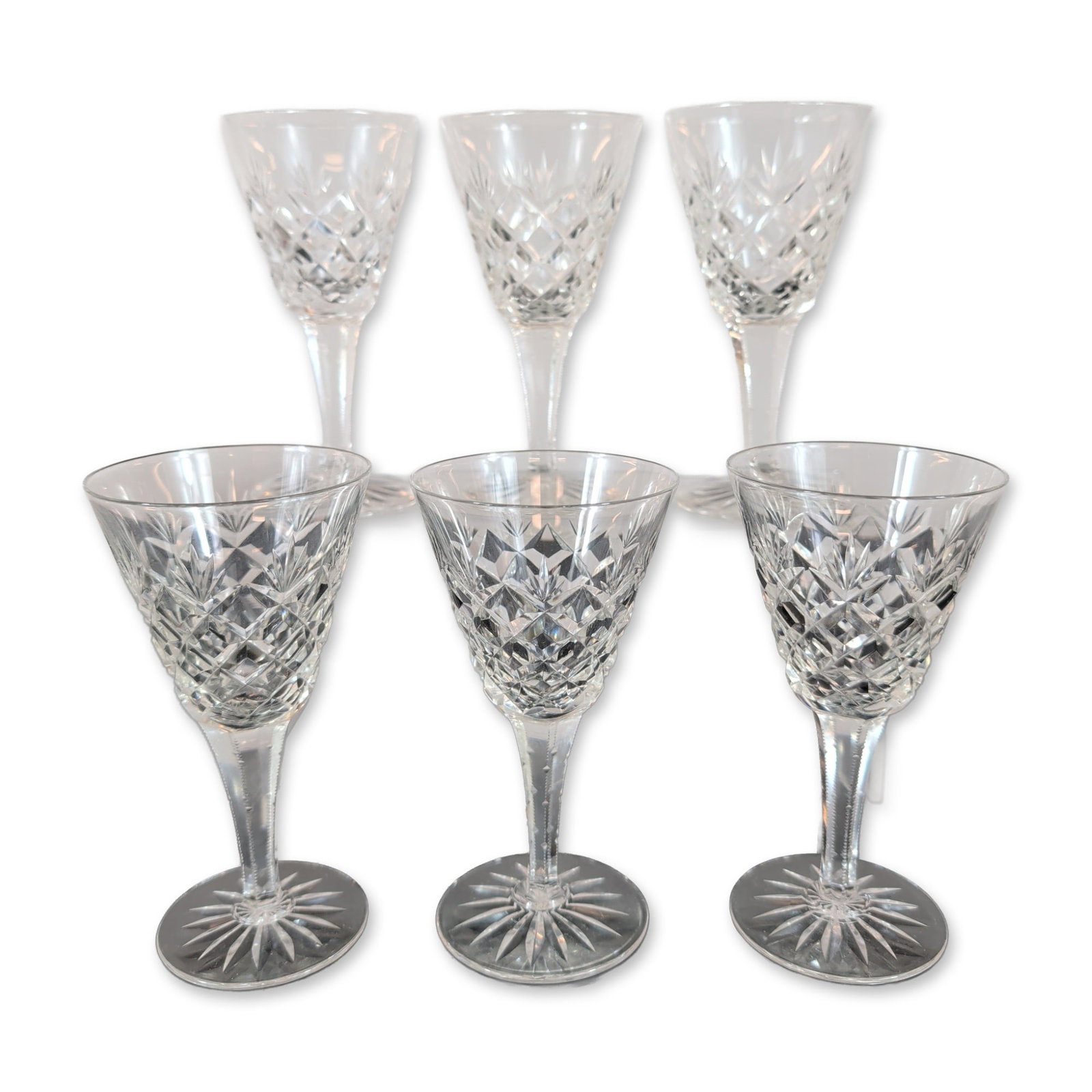 Set of Six Cut Crystal Sherry Glasses: A set of six lead crystal Sherry Glasses. Each glass features a bowl decorated with diamond-cut bands and vertical fan motifs, supported by a multi-faceted stem with notched edges. The circular feet