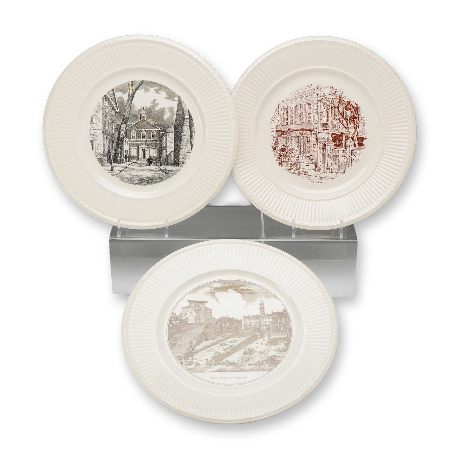 3pc Wedgwood Commemorative Earthenware Plates with Travel and Historical Themes: A trio of commemorative and souvenir earthenware plates manufactured by Wedgwood, England. Each plate is crafted from cream-colored earthenware, commonly known as Queensware, and features a circular t