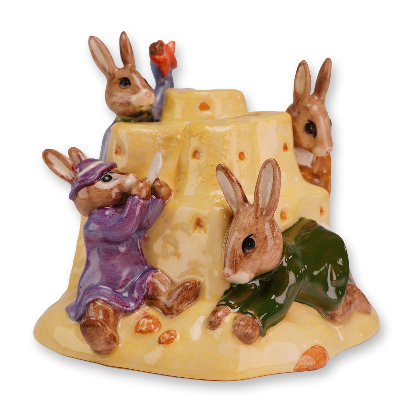Royal Doulton Bunnykins Prototype Sandcastle Money Bank: The piece features four anthropomorphic rabbits dressed in human attire, including a purple coat and hat, a dark green jacket, an orange jacket, and a blue dress with red floral patterns. They are pos