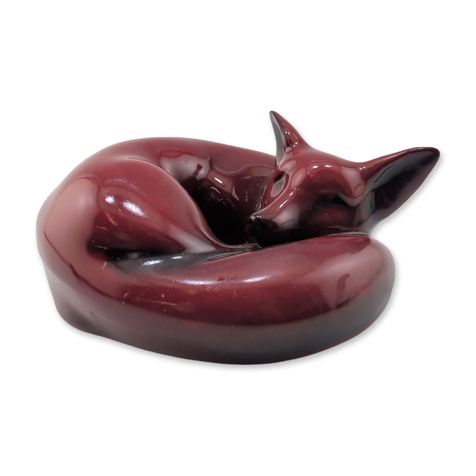 Royal Doulton Flambe Figurine, Curled Fox HN147D: Ceramic figurine depicting a curled fox in a sleeping position. The piece features the factory signature oxblood flambe glaze with deep red tones and dark shaded highlights. Marked to the underside wi