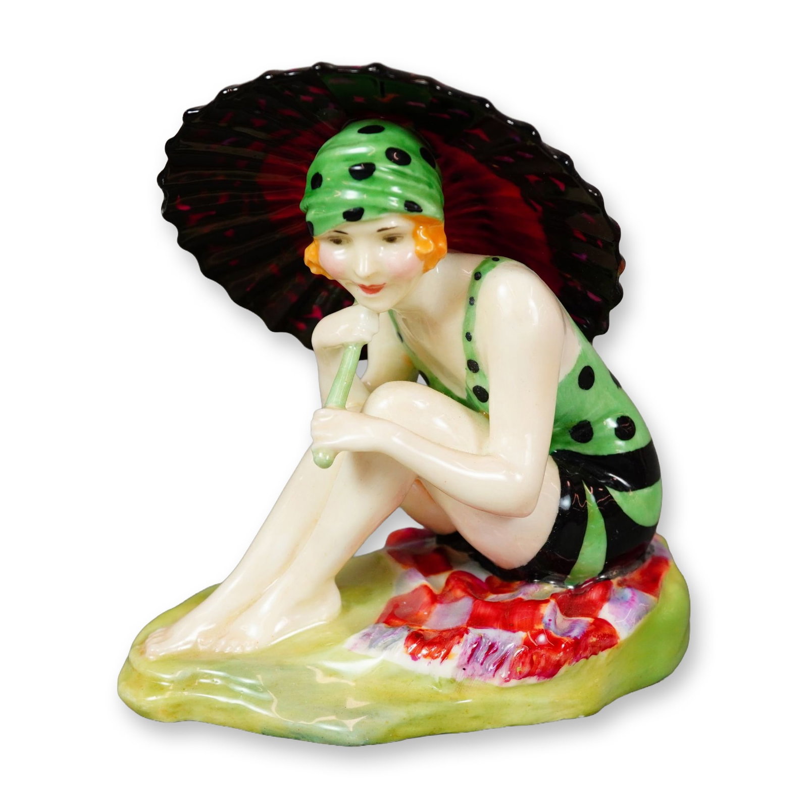 Royal Doulton Porcelain Figurine, Sunshine Girl HN1344: Royal Doulton figurine designed by Leslie Harradine. Depicts a seated woman wearing a green polka-dotted bathing suit with black accessories, holding a painted parasol. Rendered in multicolor with det