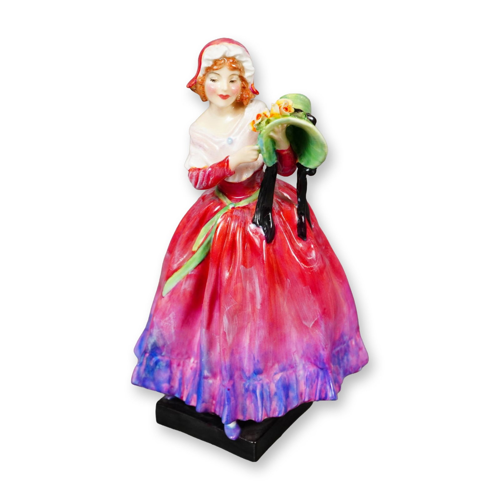 Royal Doulton Bone China Figurine, New Bonnet HN1957: Part of the Harradine Classics collection. Designed by Leslie Harradine. Hand painted figure, depicts a young woman in a pink gown with purple hues. She is holding a green bonnet with yellow flowers. 