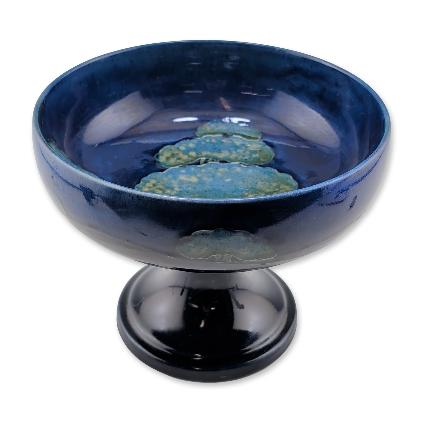 Moorcroft Pottery Footed Bowl, Moonlit Blue: Featuring tube-lined and hand-painted stylized trees in mottled green and light blue tones against a deep cobalt ground. The exterior and flared pedestal base are finished in a rich, high-gloss dark b