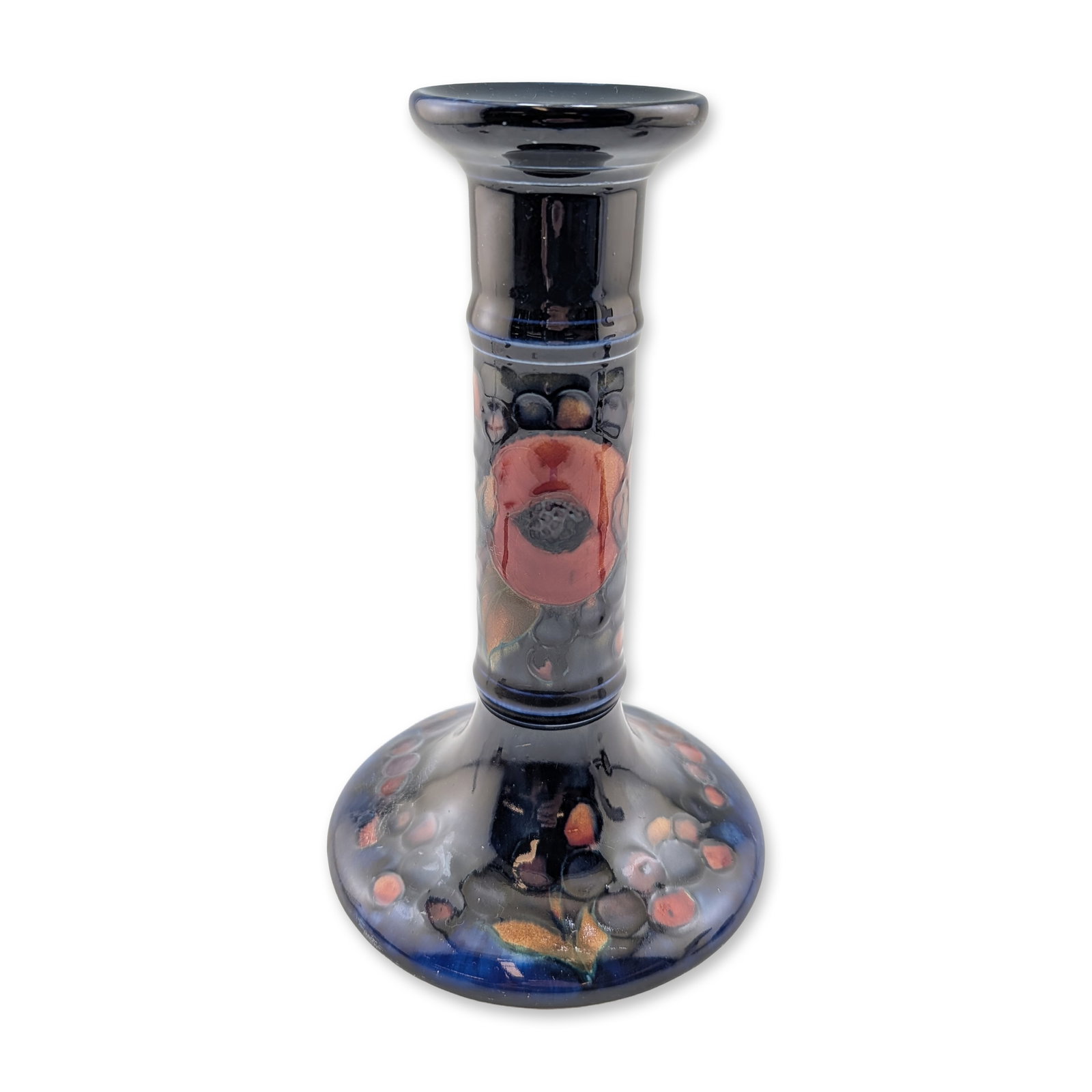 Moorcroft Pottery Candlestick, Pomegranate: Featuring hand-painted tube-lined decoration of pomegranates, grapes, and berries against a deep cobalt blue ground. The earthenware form is designed with a flared rim, a baluster stem, and a wide, sp