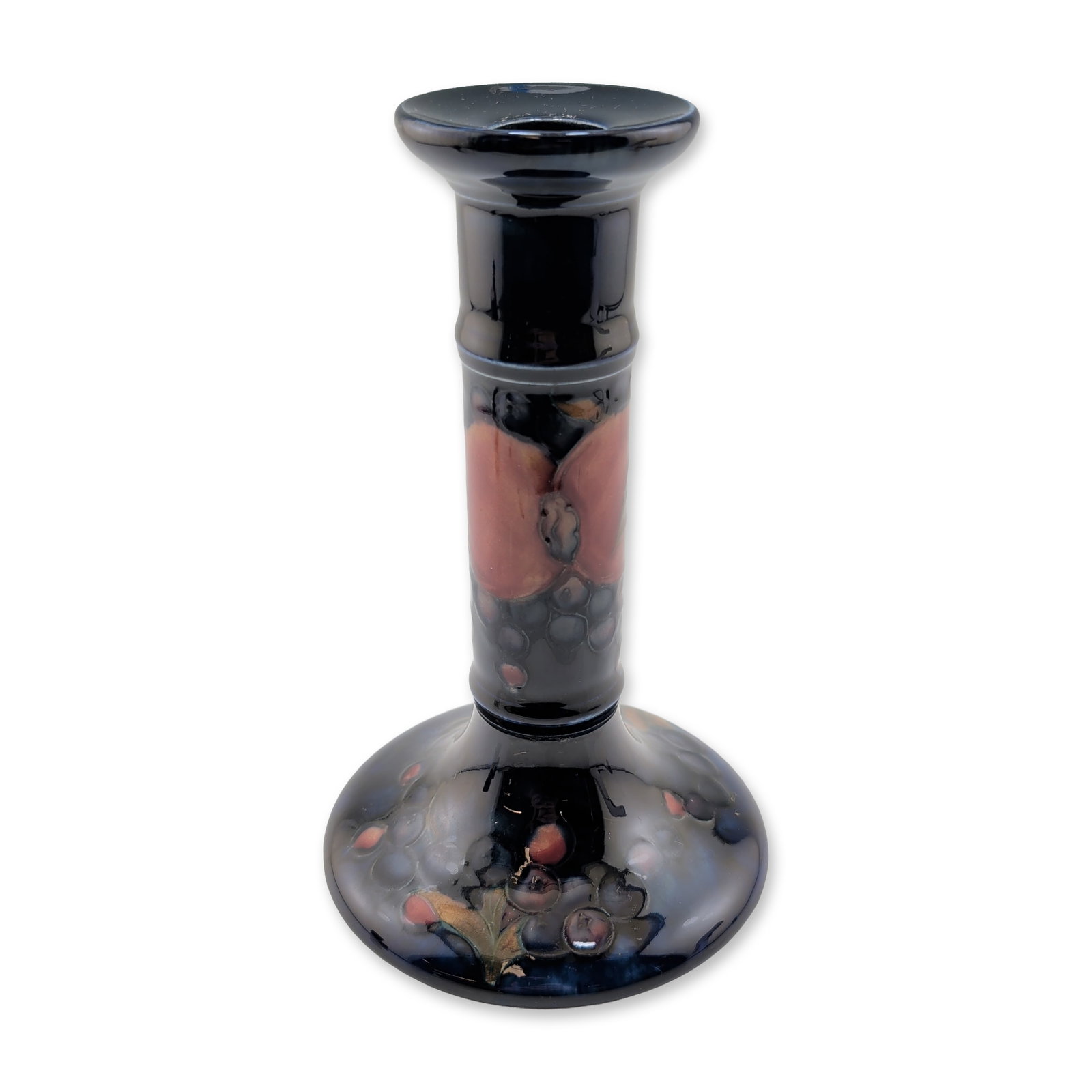 Moorcroft Pottery Candlestick, Pomegranate: Featuring hand-painted and tube-lined fruit decoration against a deep cobalt blue ground. The design includes a large pomegranate and clusters of grapes in shades of red, purple, and green. The form i
