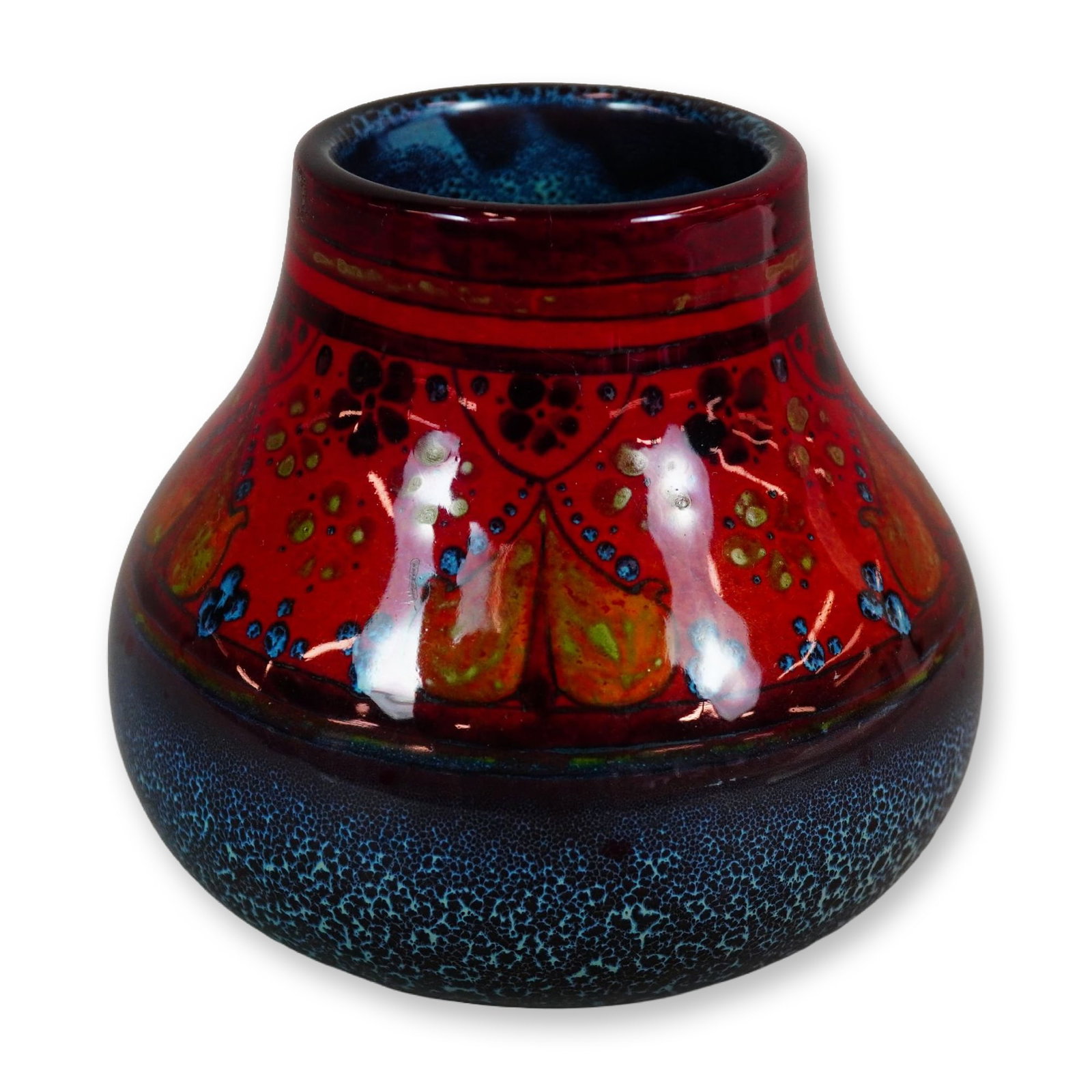 Royal Doulton Flambe Sung Vase: A small squat vase with a rounded, bulbous body and a short, sturdy neck. It is finished in a red flambe glaze with blue and yellow tonal accents, decorated with a Persian-inspired floral motif. The u