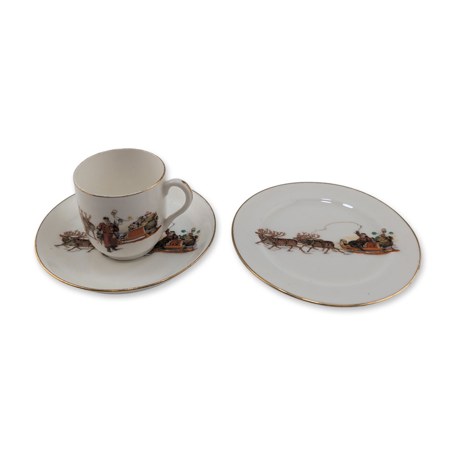 3pc Royal Doulton Christmas Series Ware Cup and Saucers: Comprising a small cup, saucer, and side plate. Each piece features a transfer-printed holiday scene depicting Santa Claus in a sleigh pulled by reindeer, accented with hand-applied gold-gilt trim alo