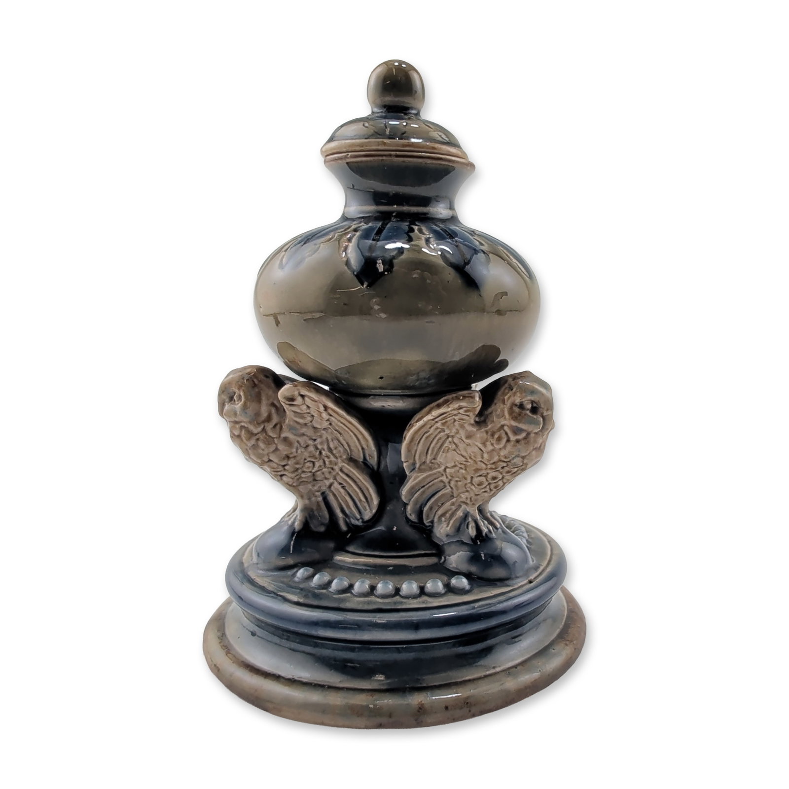 Doulton Lambeth Stoneware Lidded Owl Inkwell: This salt-glazed stoneware piece features a bulbous body on a flared circular base with two applied owls figures with spread wings. The vessel is finished with a mottled glaze in tones of olive, slate