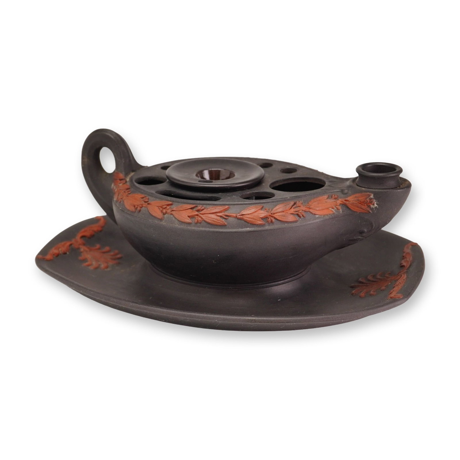 Wedgwood Black Basalt and Rosso Antico Sprigged Inkstand and Pen Holder: A Wedgwood stoneware inkstand and pen holder assembly, modeled in the neoclassical form of a classical oil lamp. The set is crafted in matte black basalt and features an oval under-tray, a lamp-form b