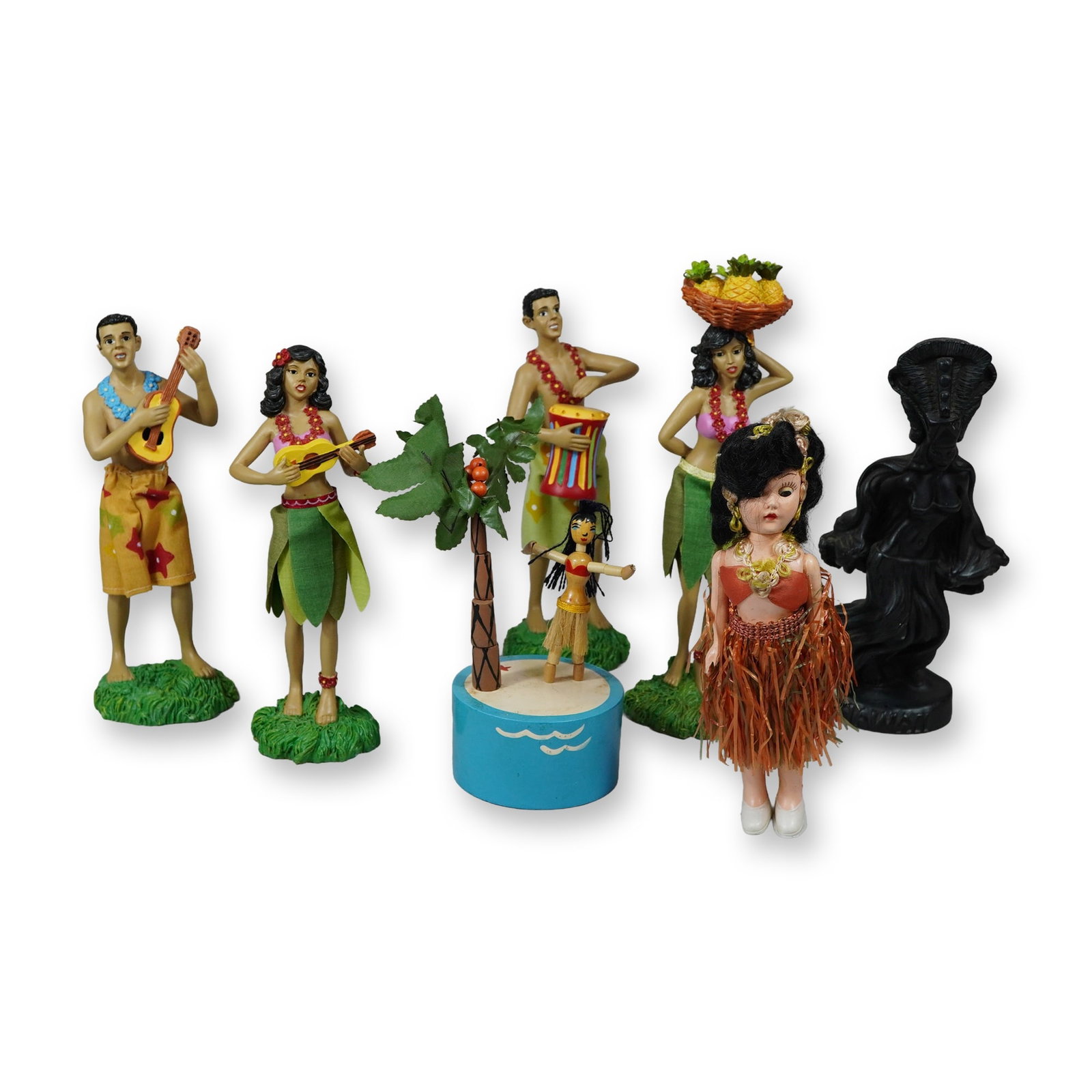 Group of Seven Hawaiian Figural Souvenir Items: Collection of seven Hawaiian-themed souvenir items featuring a mix of vintage and contemporary decorative pieces. The lot includes a dark resin or composite stylized figure by Coco Joe's of Hawaii. Al