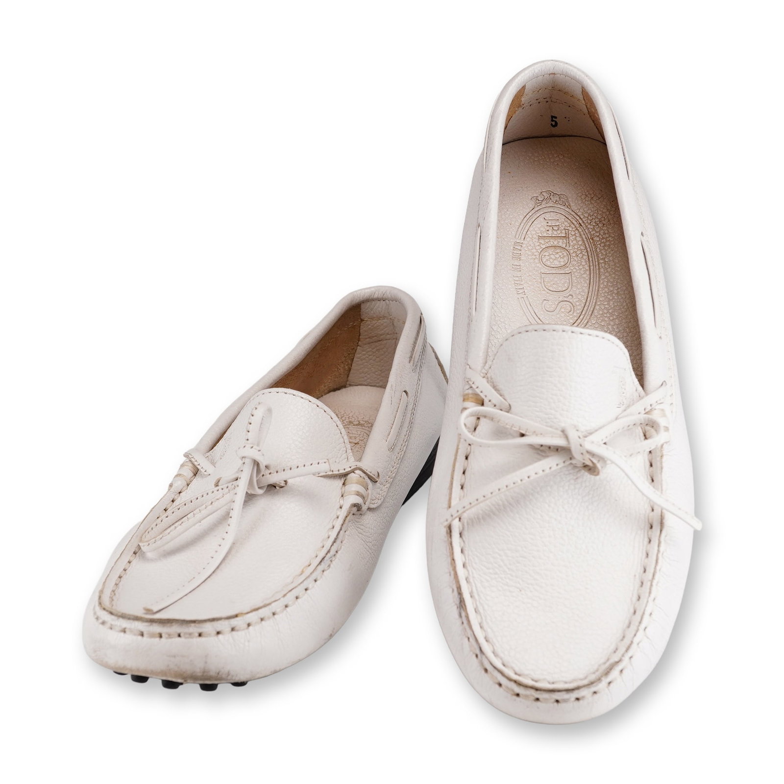 Tod's Gommino Driving White Loafers: A pair of Tod's Gommino driving loafers featuring a white hammered leather upper with a front tie bow detail. These Italian-made shoes include a full leather lining and the signature rubber pebble out