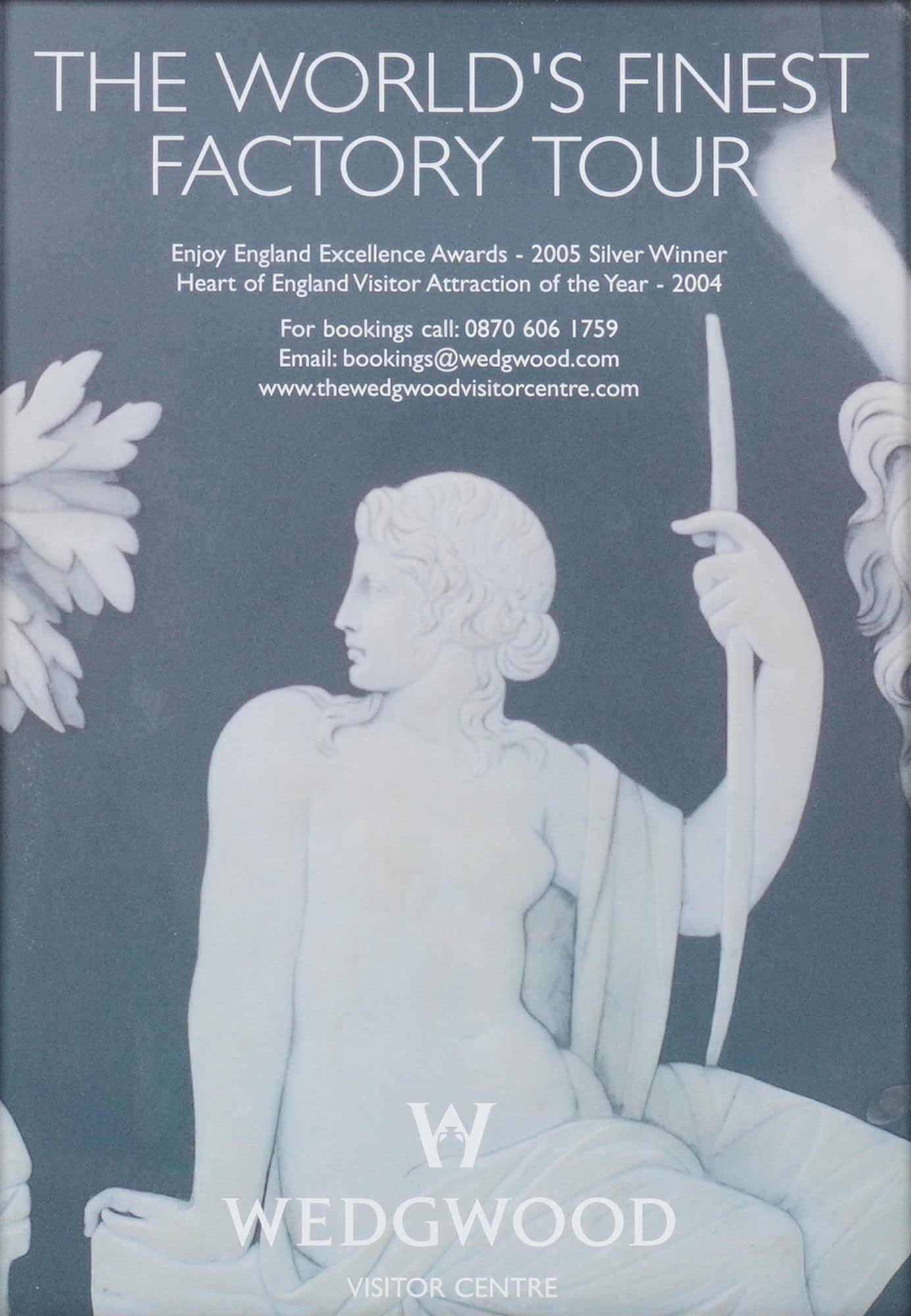 Framed Wedgwood Visitor Centre Factory Tour Advertisement Poster: A framed Wedgwood poster advertising "THE WORLD'S FINEST FACTORY TOUR," featuring a white classical figure in relief style against a dark grey background, set in a mat silver tone frame. Dimensions: F
