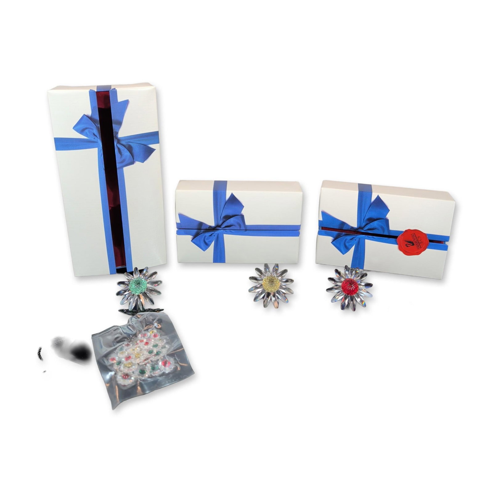 3pc Swarovski Crystal SCS Marguerite Daisy Figurines Collection with Loose Miniature Flowers: A group of three large Swarovski Marguerite daisy figurines and a collection of small flower pins in faceted lead crystal. The large daisies feature clear faceted petals surrounding centers in red, ye