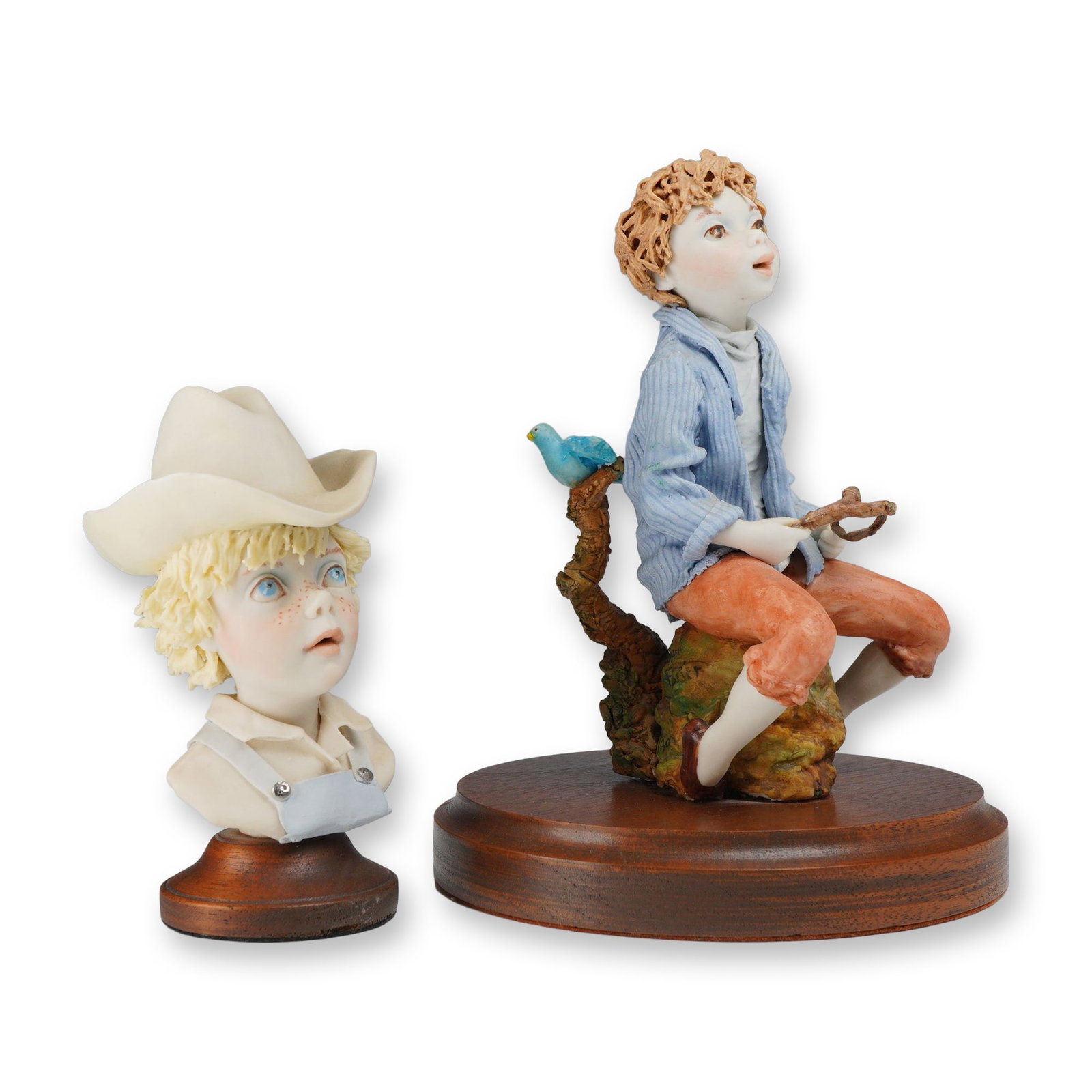 Two Bonni Porter Signed and Numbered Figurines on Wooden Bases: This lot includes two hand-painted figurines by artist Bonni Porter, each mounted on a circular dark wood base. The first is a full-figure sculpture of a young boy with curly reddish-brown hair seated