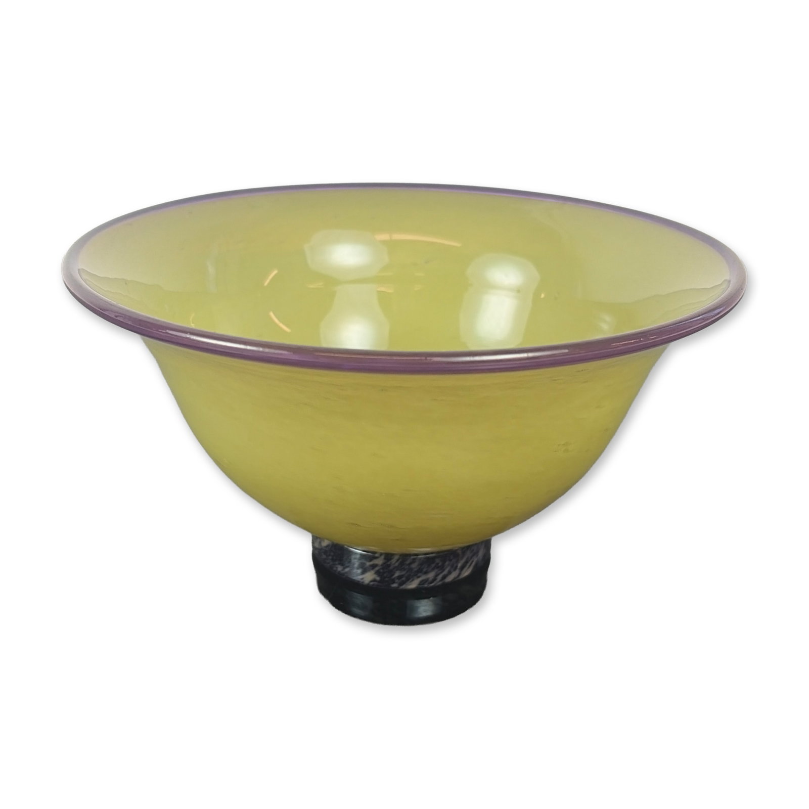 Liz Marx Studio Glass Bowl: Hand-blown glass in a wide flared form, featuring a chartreuse seeded body with an applied amethyst purple rim. The bowl sits on a small integrated cylindrical foot with a marbled finish in dark