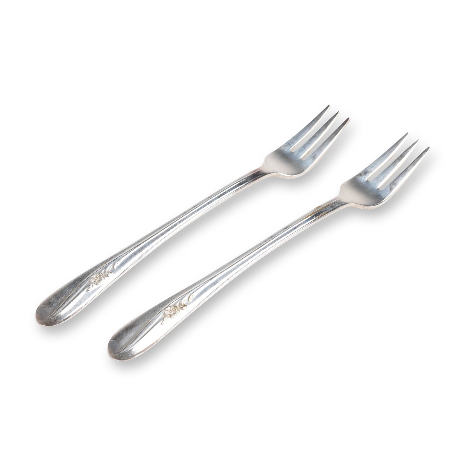 A Pair of H. & T. MFG. CO. Meadow Flower Silverplate Forks: A pair of vintage silver-plated flatware pieces in the Meadow Flower pattern, attributed to H. & T. MFG. CO. The 2pc set consists of two three-tined forks. The slender handles terminate in a subtl
