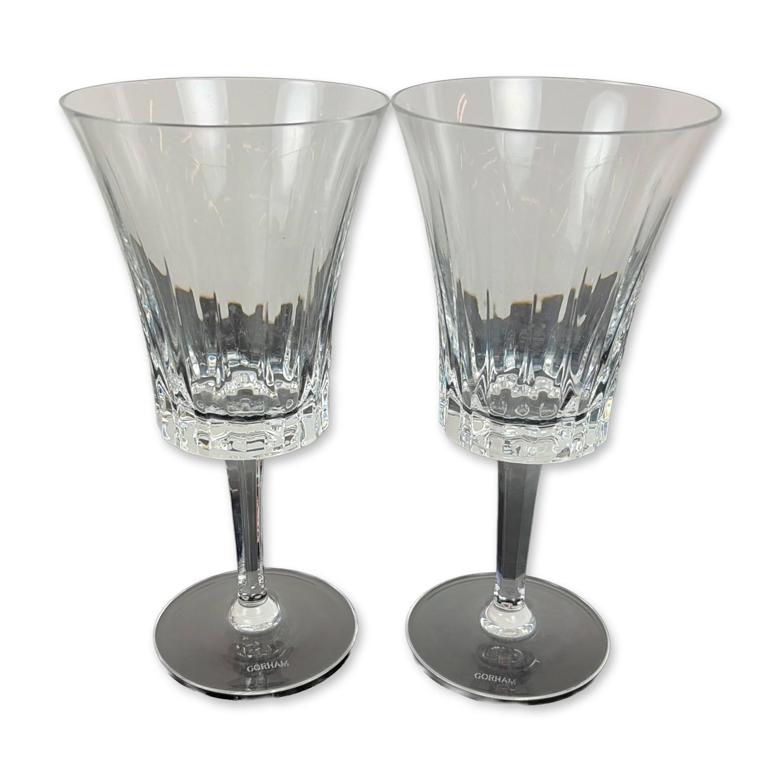 Pair of Gorham Richelieu-Rondo Water Goblets: Each vessel features a trumpet-shaped flared bowl decorated with vertical fluted cuts above a band of deep crisscross diamond accents. The stems are faceted and taper toward a circular foot. The foot 