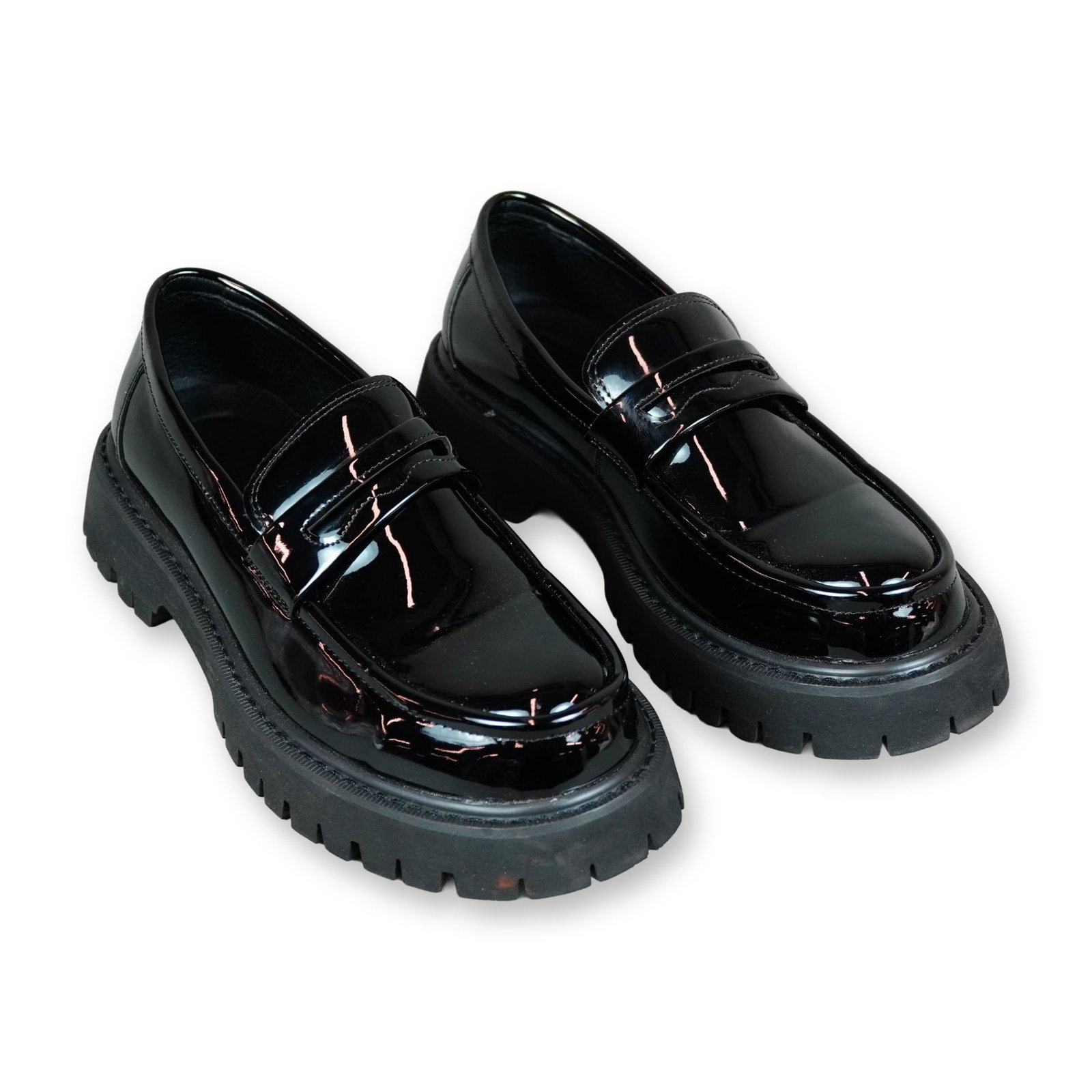 Pair of Black Patent Leather Chunky Penny Loafers: Pair of unbranded black patent leather chunky penny loafers featuring a platform lug sole. The slip-on shoes are constructed with a glossy patent leather upper, a classic penny keeper strap across the