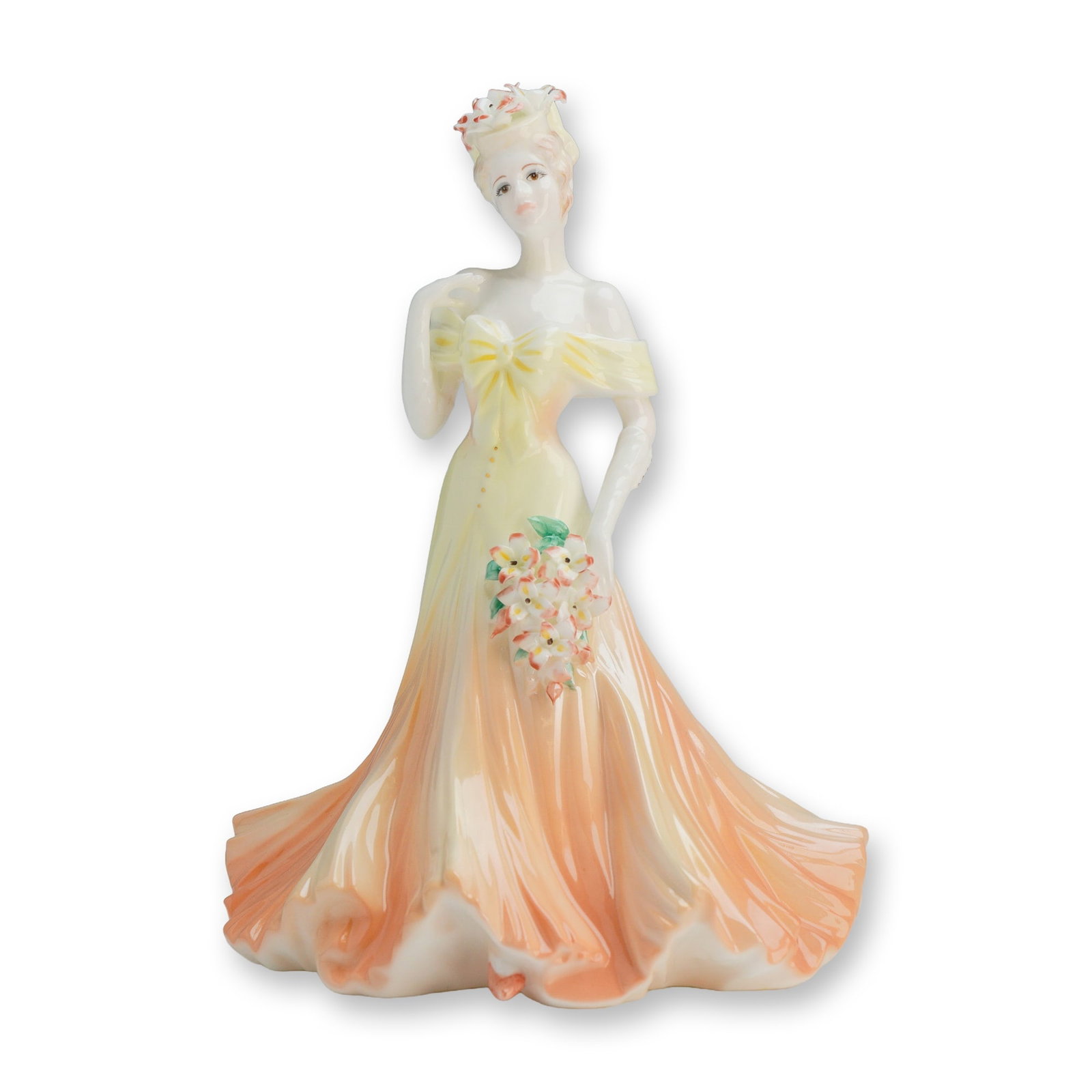 Coalport Flower Ladies Collection Figurine, Gracious Lily: This hand-decorated piece depicts a female figure in an off-the-shoulder gown featuring an ombre color transition from pale yellow to a peach-orange hue. The figure is portrayed holding a bouquet of