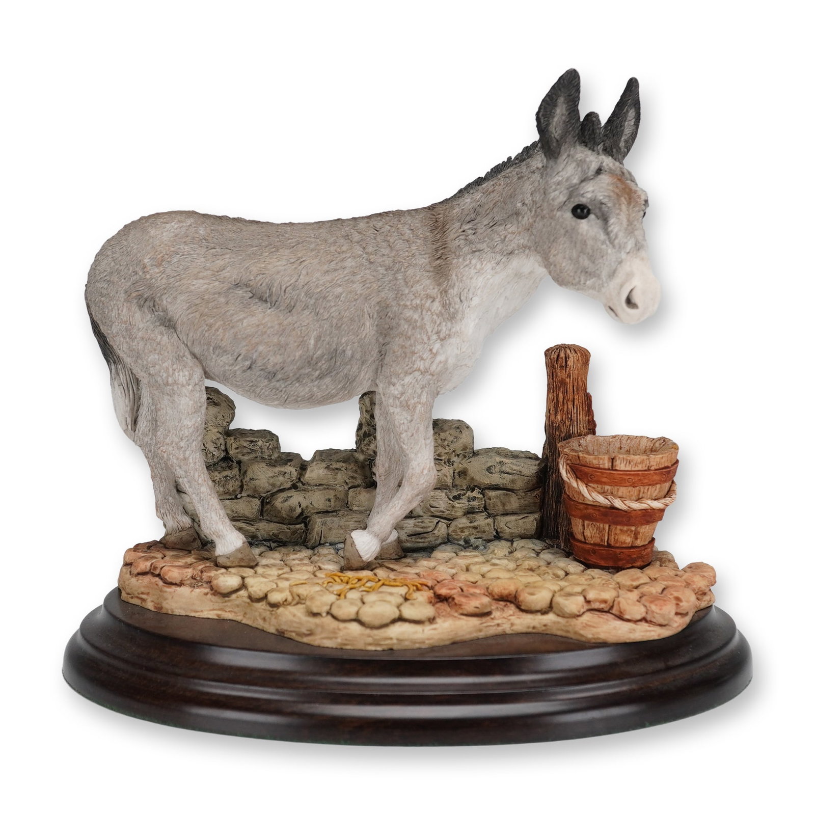 Country Artists Donkey Figurine: A hand-painted collectible figurine by Country Artists, model number 01033, titled Donkey. The piece depicts a grey donkey standing in a detailed rural scene featuring a low stone wall, a wooden