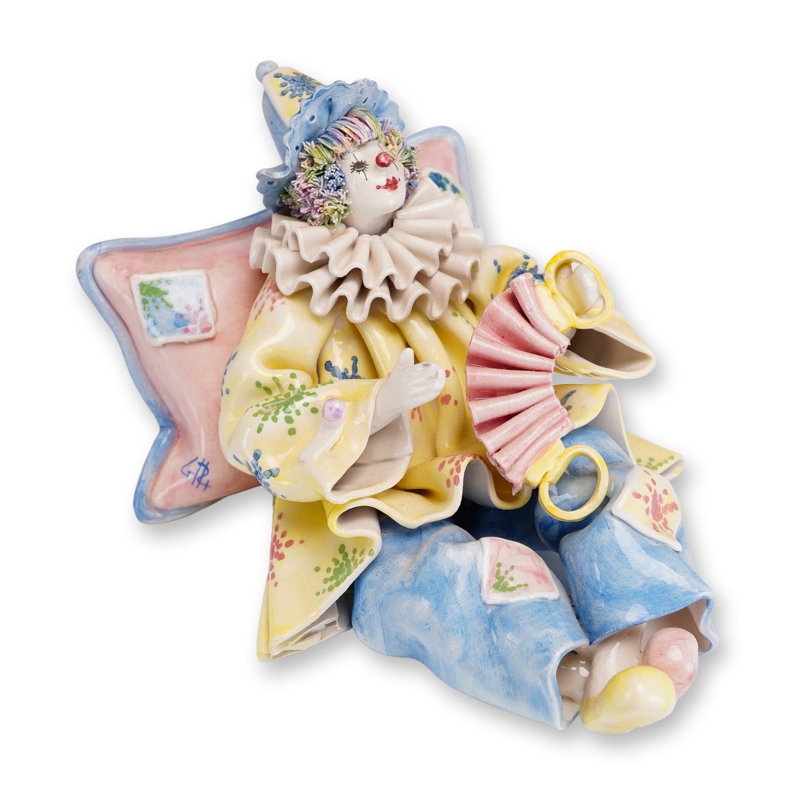 Gump's Italian Figurine, Reclining Clown with Concertina: This hand-painted Italian porcelain figurine, produced for Gump's of San Francisco, depicts a reclining clown in a relaxed pose. The figure leans against a large, star-shaped pink pillow while