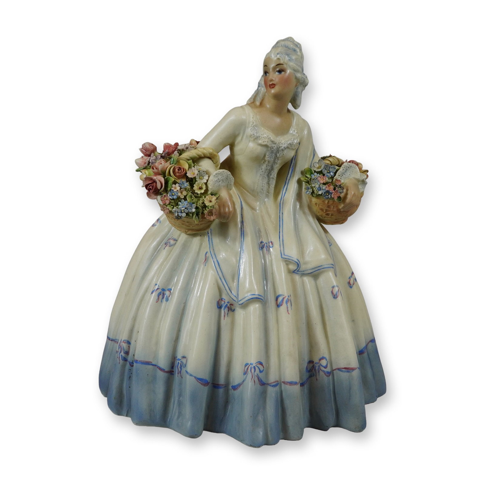 Arturo Pannunzio Ceramic Donna with Flower Baskets: Arturo Pannunzio (Italian, 1891-1953). Polychrome glazed ceramic figurine depicting an elegantly dressed woman in 18th-century style attire. The figure is modeled in a walking pose, supporting two wov