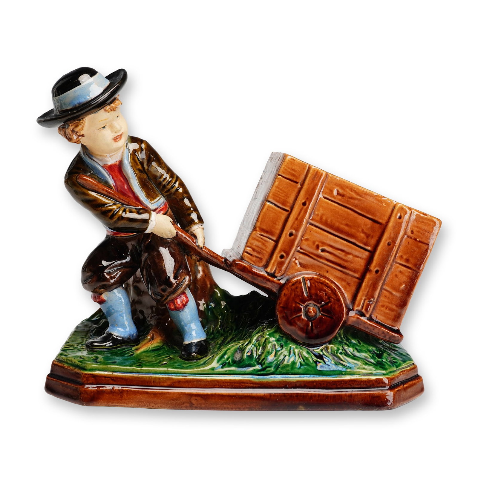 Bernard Bloch, Boy Pulling Cart Figural Spill Vase: This late 19th or early 20th-century Bohemian majolica figural group was produced by the Bernard Bloch factory in Eichwald. The glazed earthenware piece depicts a young boy in traditional rustic attir
