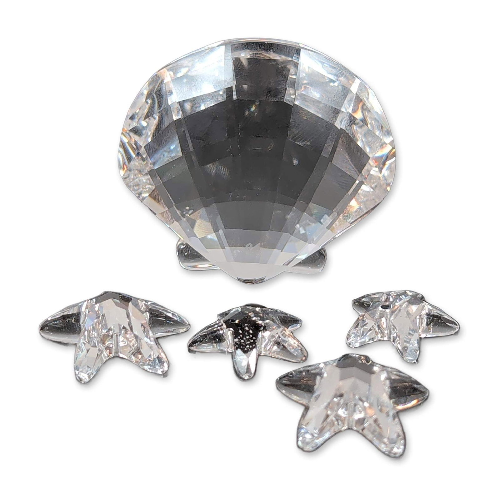 5pc Swarovski Crystal Scallop Shell and Starfish Paperweight: Swarovski. Scallop shell figurine in faceted clear lead crystal, featuring four integrated five-pointed starfish. Laser-etched swan maker's mark to the underside. Dimensions: 2"L x 1.75"W. Weight: