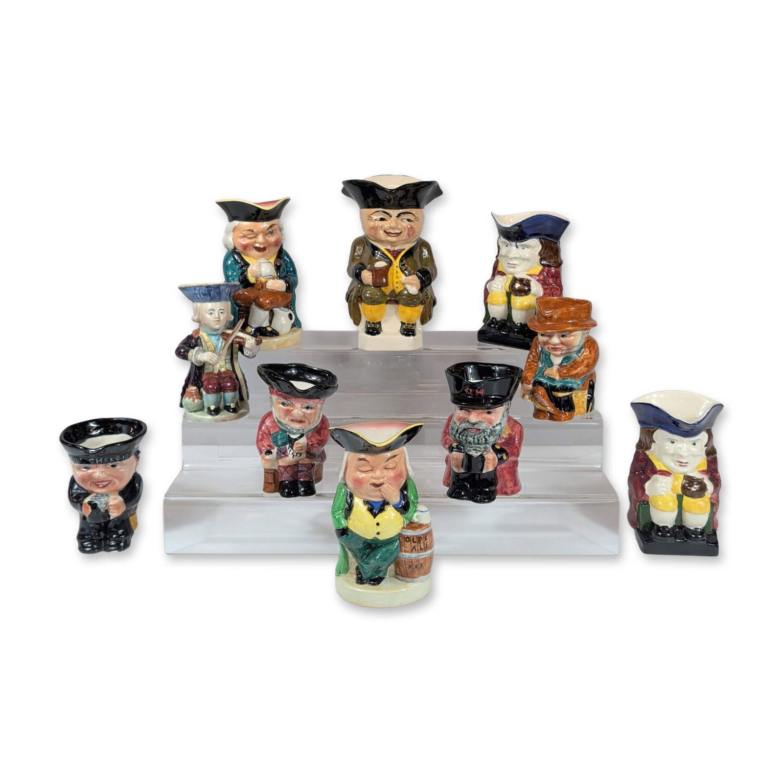 10pc English Ceramic Character Jugs: Collection of English character jugs in polychrome glazed earthenware, featuring a variety of traditional figures in 18th and 19th-century attire. Marks on the bases include black stamps for Genuine B