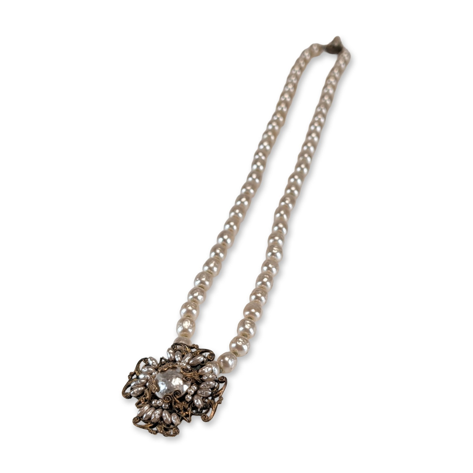 Miriam Haskell Vintage Faux Pearl Necklace: Miriam Haskell. Single-strand necklace featuring cream-colored baroque faux pearls and an ornate gold-tone filigree focal piece. The centerpiece is constructed from multi-layered filigree metal and fu