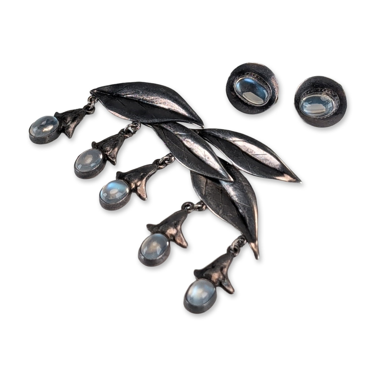 Sterling Silver and Moonstone Earrings and Brooch Set: Sterling silver jewelry group, featuring a foliate brooch and matching screw-back earrings. The brooch incorporates three stylized leaf forms with five dangling pendant drops, each terminating in a fl