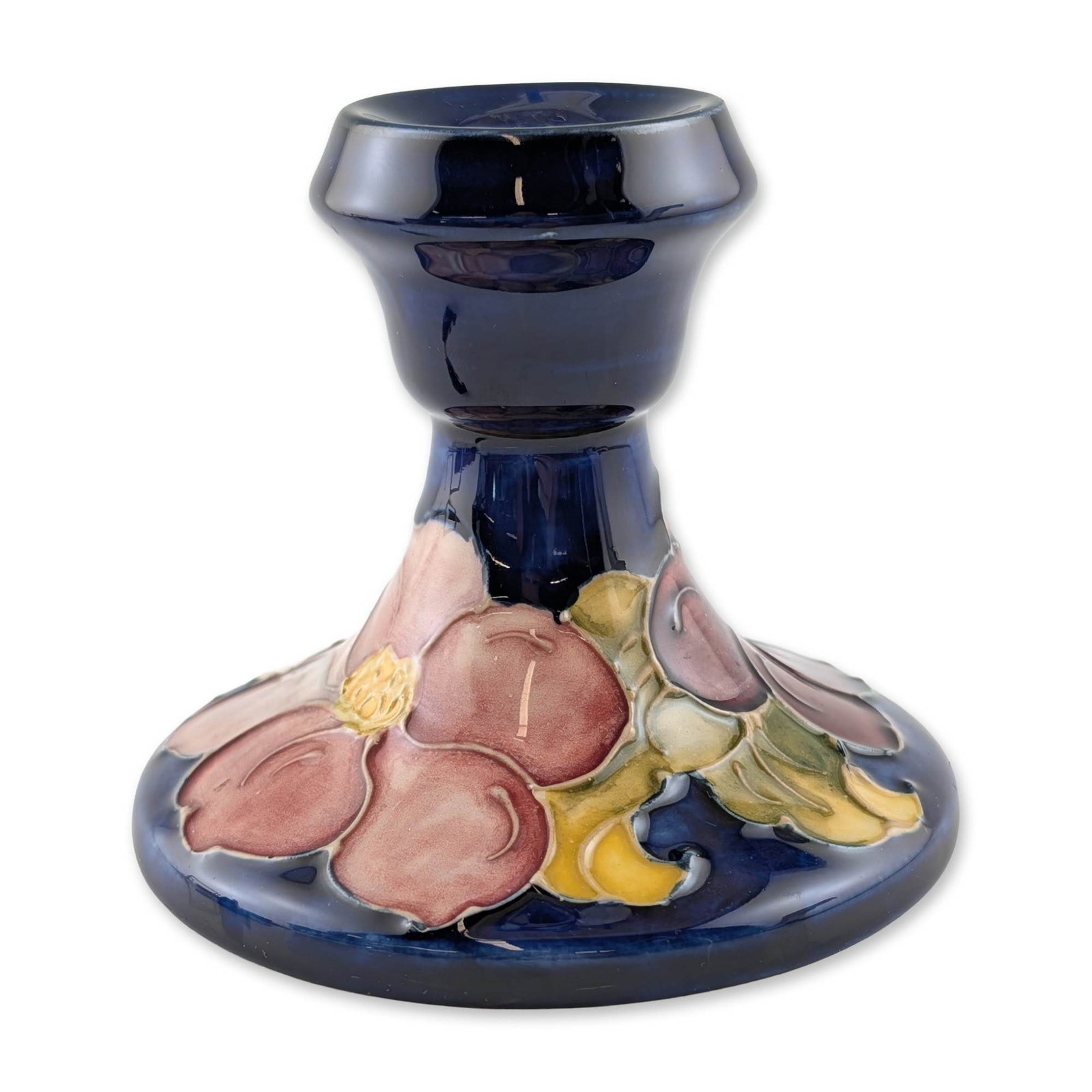 Moorcroft Clematis Pattern Ceramic Candlestick: Walter Moorcroft, circa 1949. Earthenware candlestick featuring the Clematis pattern with tube-lined and hand-painted floral decoration in pink, purple, and yellow against a cobalt blue ground. Base