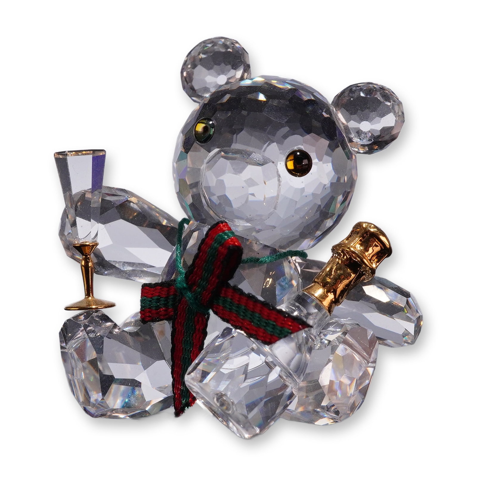 Swarovski Crystal Kris Bear Celebration Figurine: Swarovski clear faceted lead crystal figurine depicting the seated Kris Bear Celebration, model number 238168. The figure features black and amber crystal eyes, a black nose, and a red and green fabri