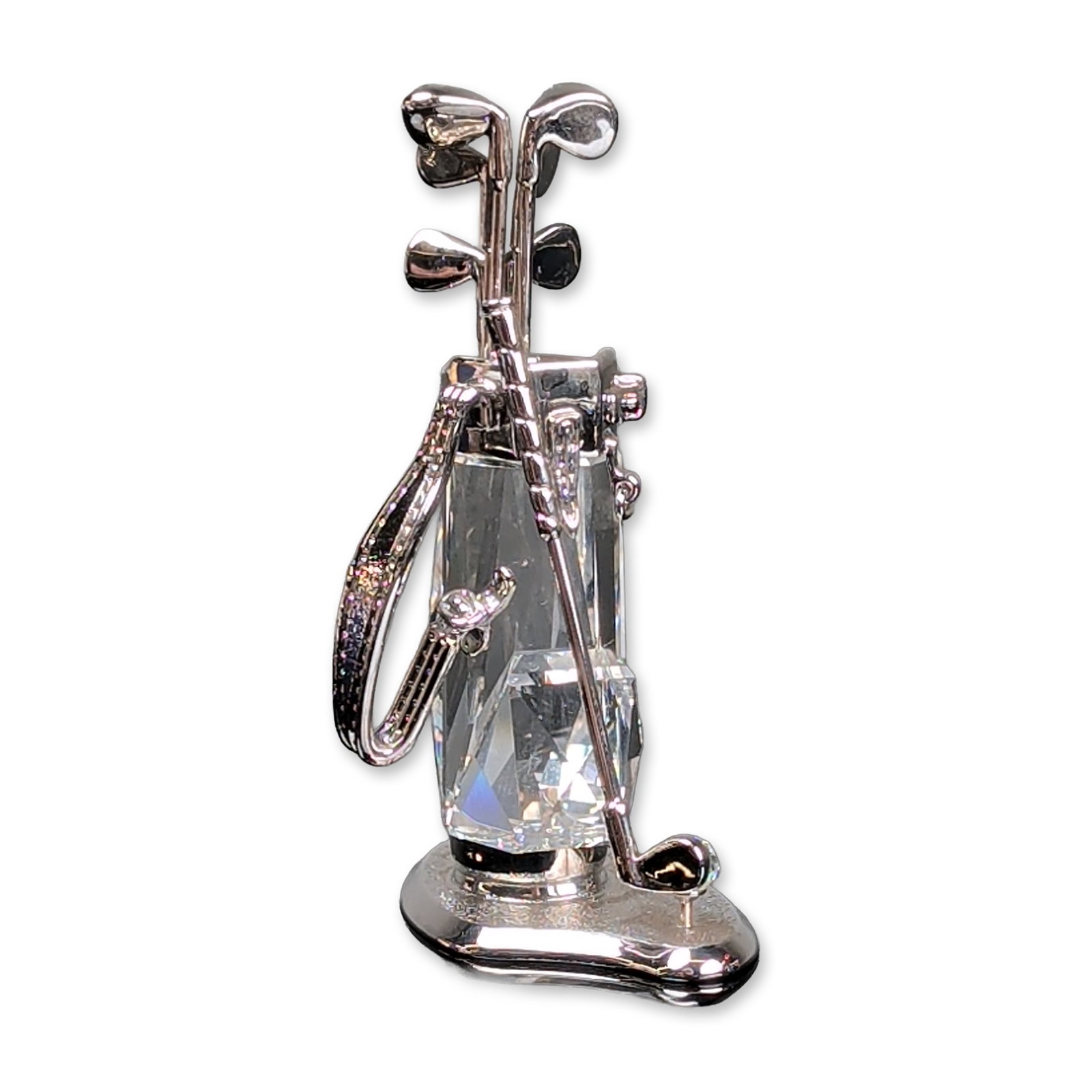 Swarovski Crystal Memories Figurine, Golf Trophy with Rhodium: Swarovski golf bag figurine. Faceted clear crystal and rhodium metal, featuring integrated golf clubs, a carrying strap, and a polished circular base. Accompanied by original blue Swarovski branded pr