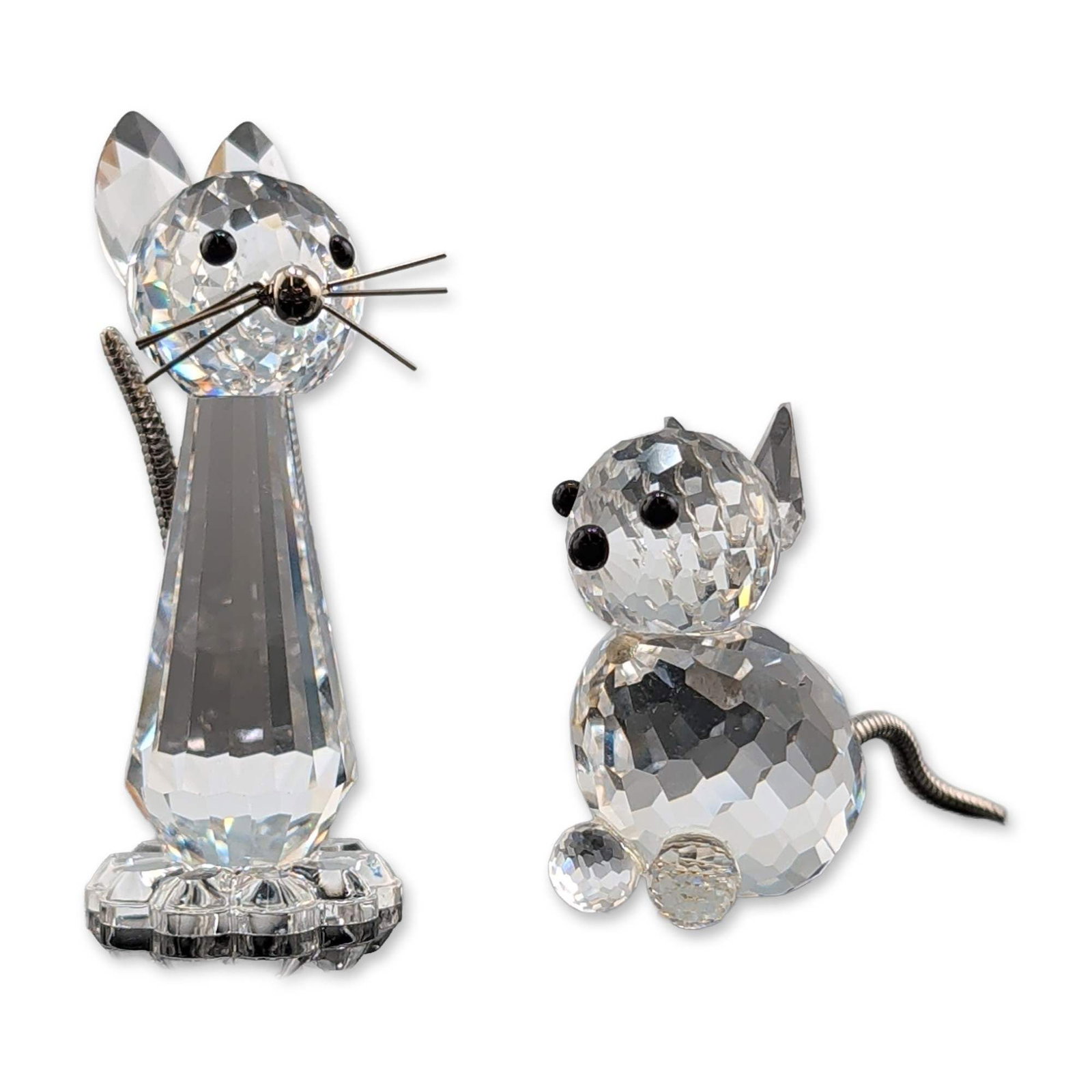 Two Swarovski Silver Crystal Cat Figurines: Two Swarovski Silver Crystal cat figurines in faceted clear lead crystal with metal accents, featuring one sitting cat with a rounded faceted body and one elongated cat with wire whiskers. Both figure